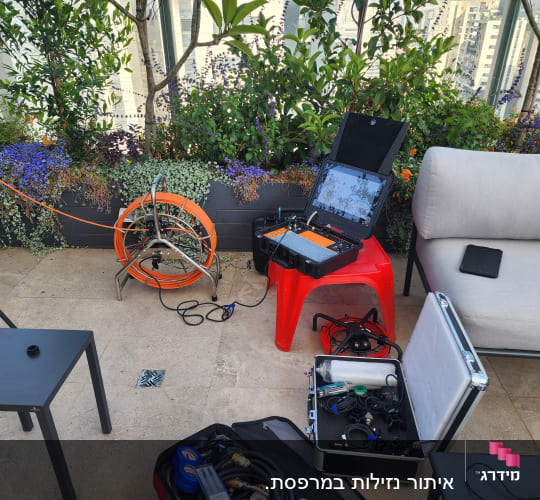 ציוד איתור נזילות עם כבל כתום ומחשב נייד פתוח